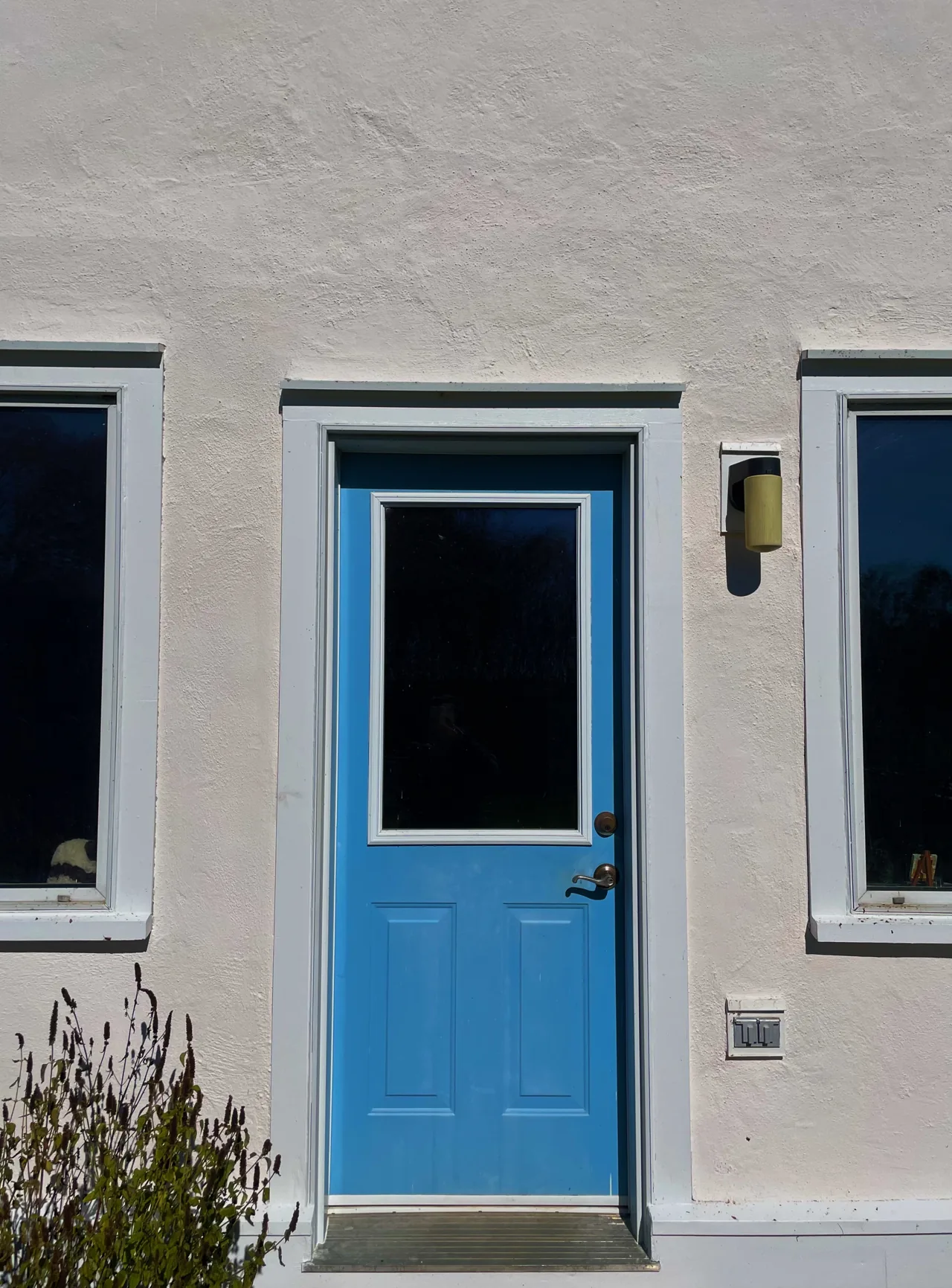 Bright blue entry door with white trim on a pale exterior wall