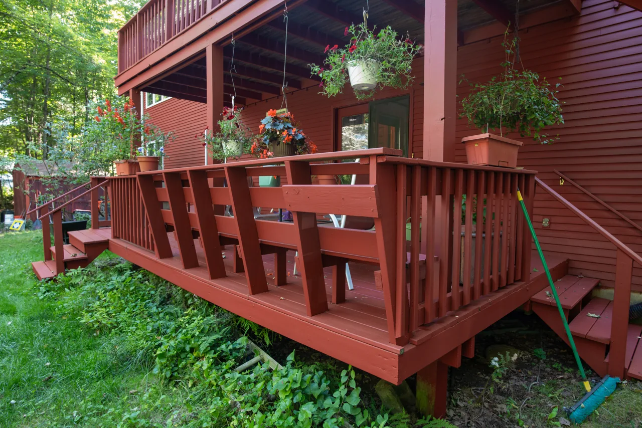 Red porch railing, posts and entry steps with hanging plants
