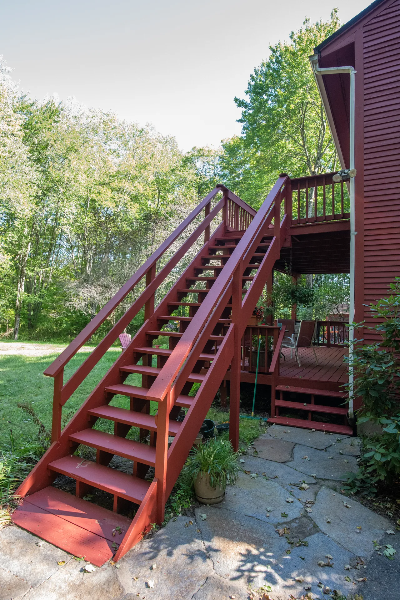 Red exterior staircase and railings beside a red house and porch