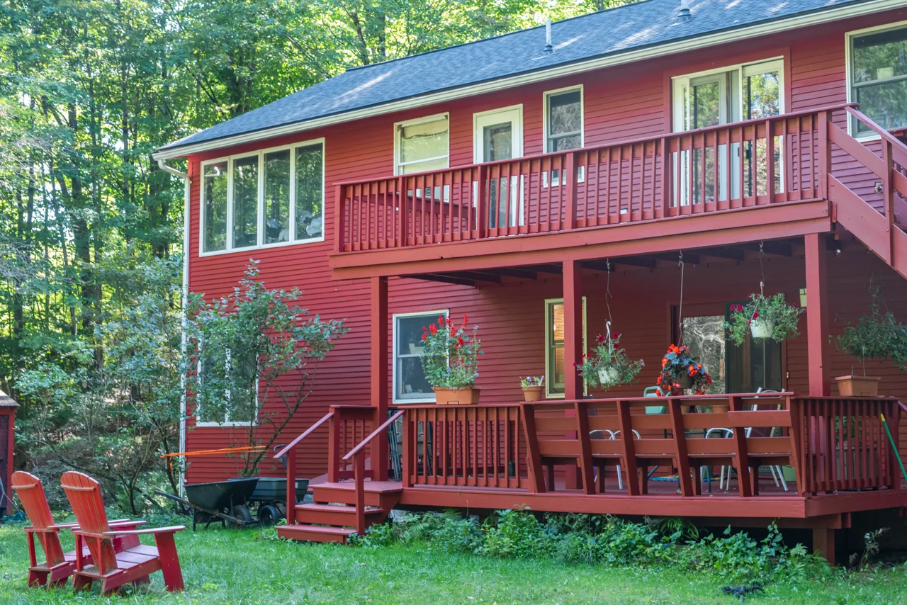 Red two-story home with a balcony and covered porch