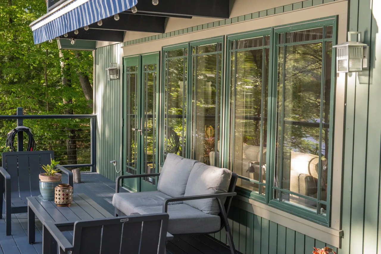 Green porch with painted trim, tall windows and seating