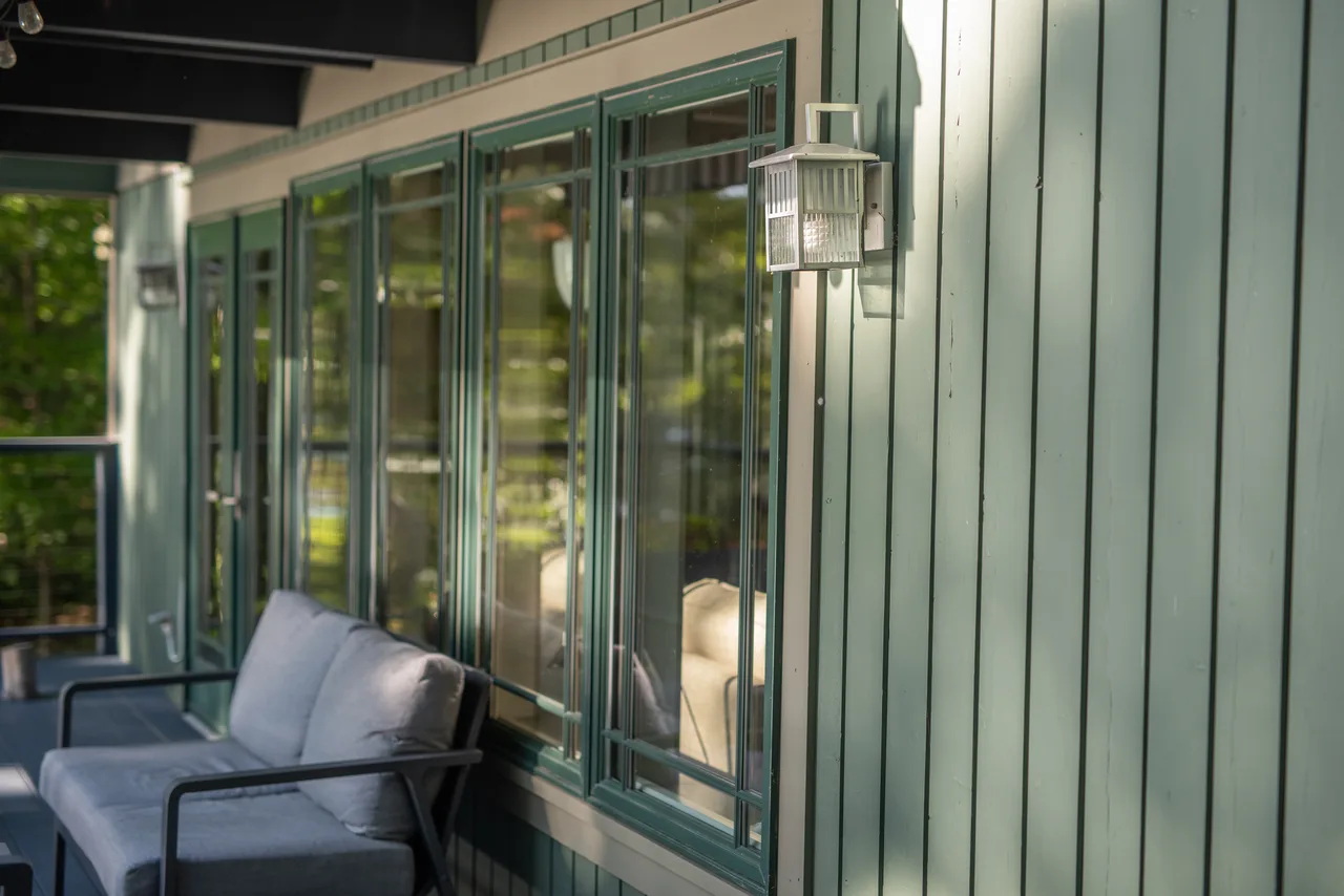 Green porch wall with windows, a wall lantern and outdoor chairs