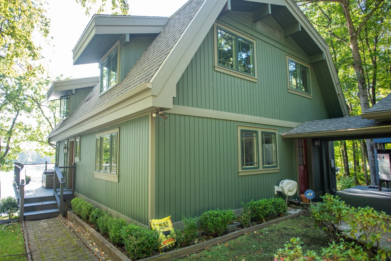 Sage green house with vertical siding among trees