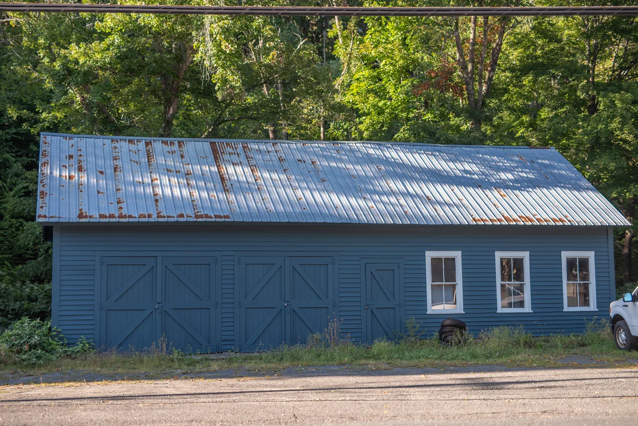 Blue barn with large sliding doors, white-trimmed windows and a metal roof