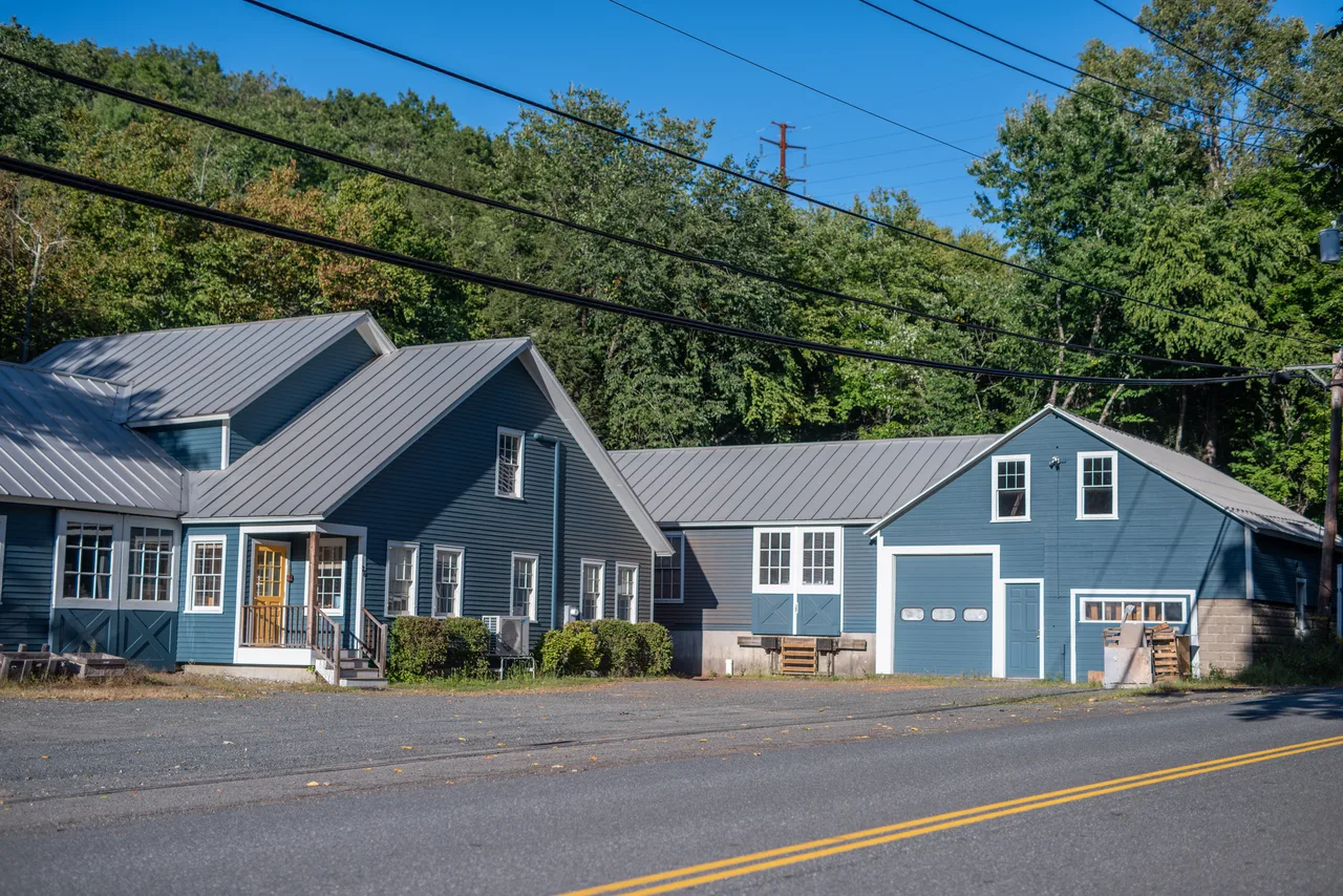 Blue house and matching detached garage beside a road