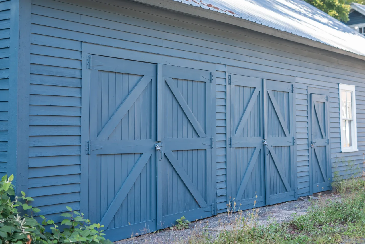 Blue cross-braced barn doors and siding beneath a metal roof