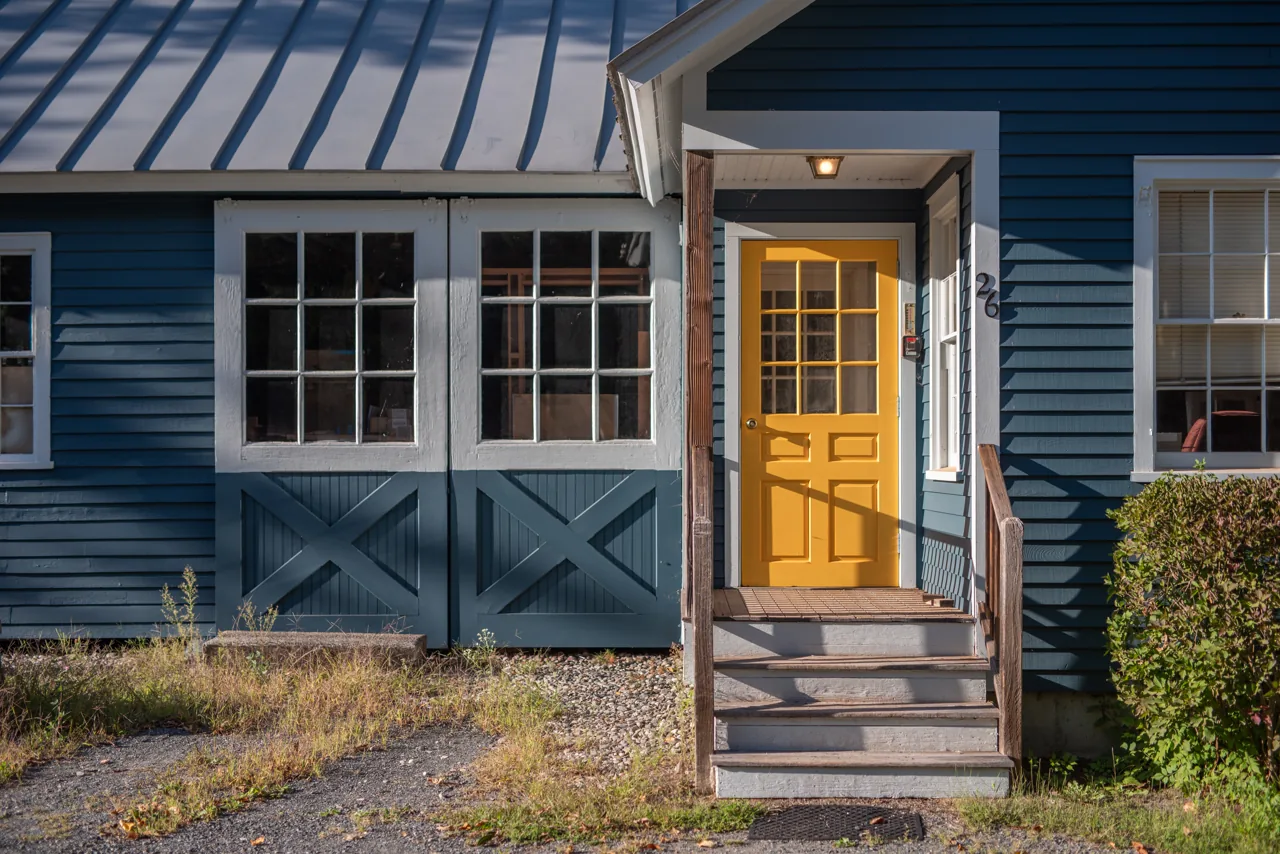 Golden yellow front door framed by blue siding and white windows